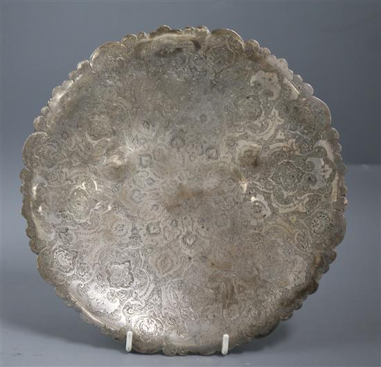 A Persian engraved white metal circular dish, on three ball feet, 24cm.